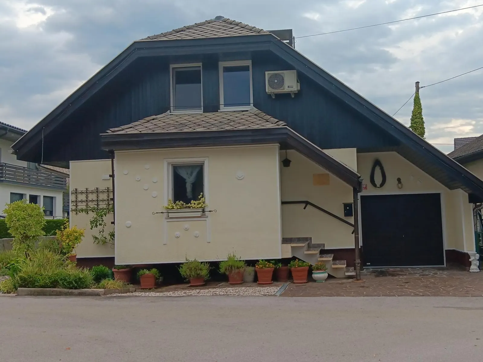 Hiša Piber s ceste, z garažo in rožami pred vhodom
