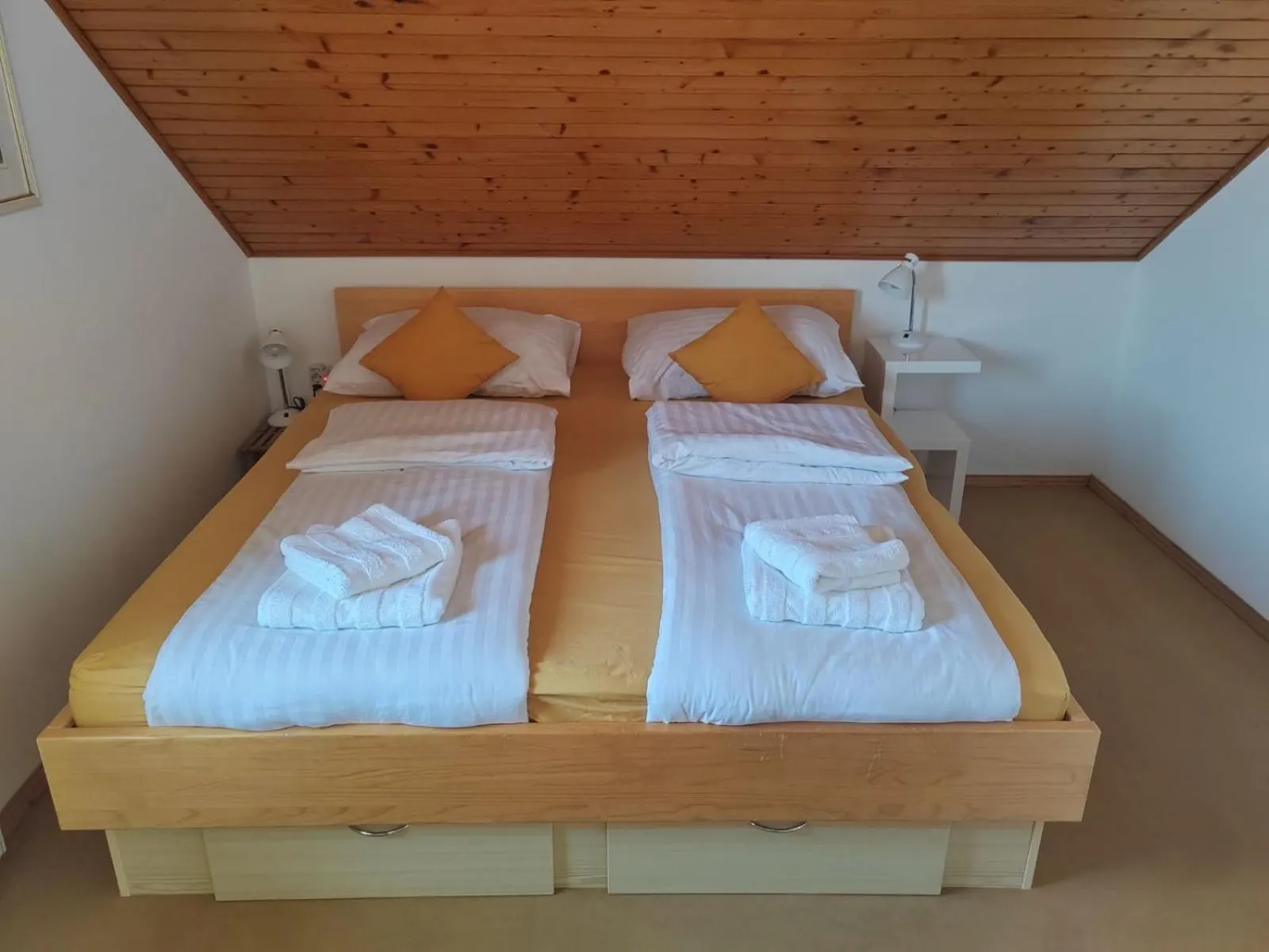Spalnica z leseno zakonsko posteljo in rumeno posteljnino
